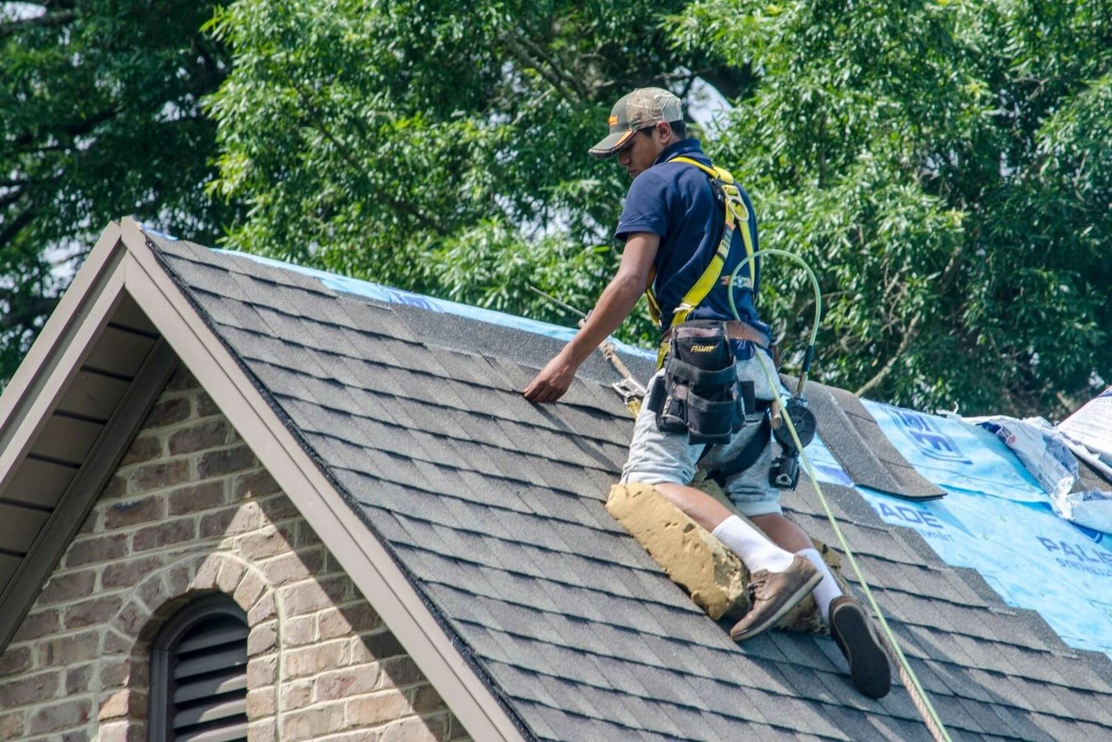 St. Louis roof repair crew from John Beal Roofing replacing storm-damaged shingles on a two-story home